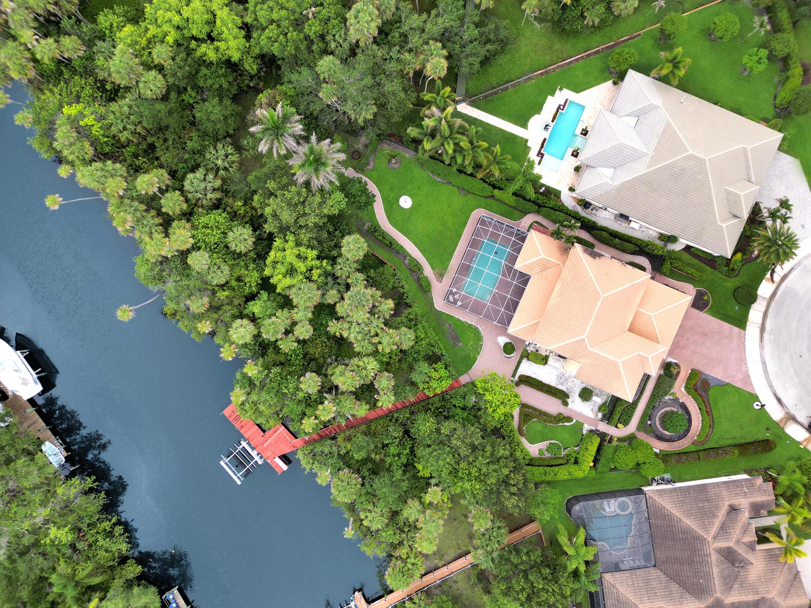 Aerial view of a waterfront house with a pool, dock, and lush landscaping — 299 SW Lost River Road, Stuart FL 34997, STUART, FL