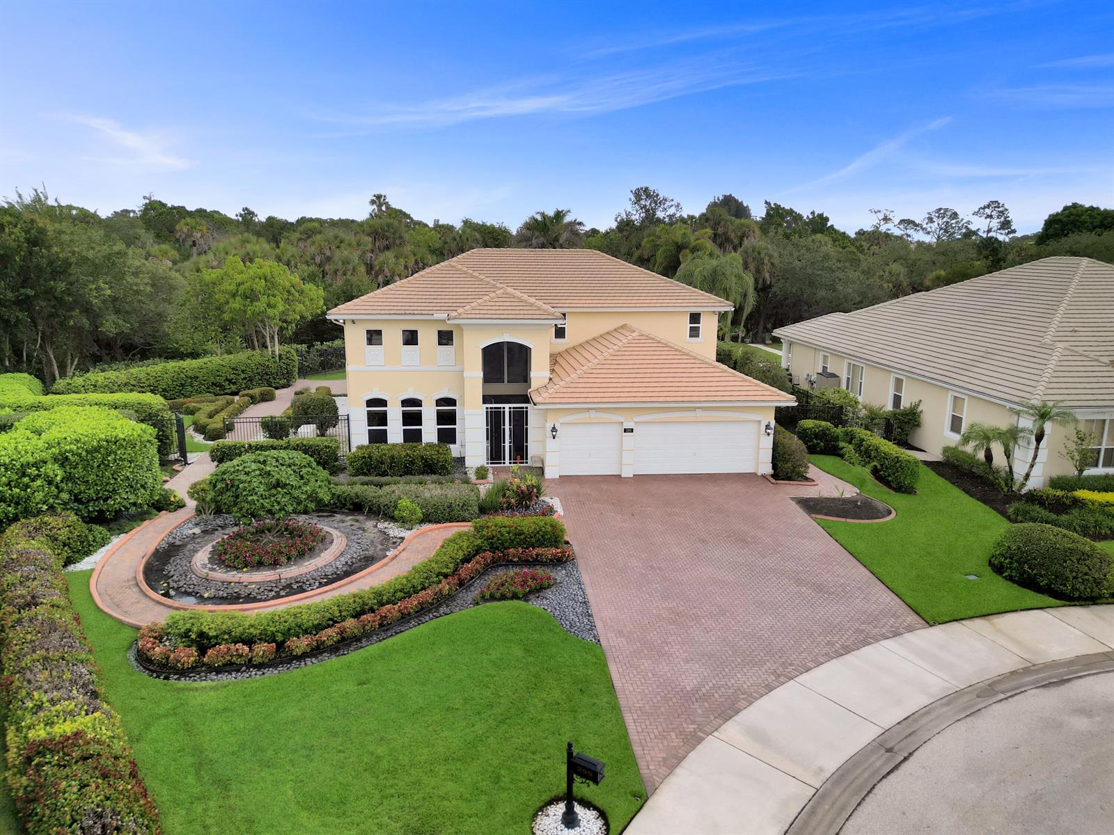An aerial view shows a two-story yellow house with a tiled roof and brick driveway — 299 SW Lost River Road, Stuart FL 34997, STUART, FL