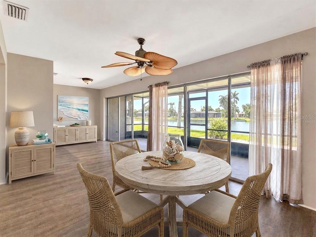 A dining area with a round wooden table, wicker chairs, and sliding glass doors — 356 PEPPERTREE ROAD, VENICE, FL