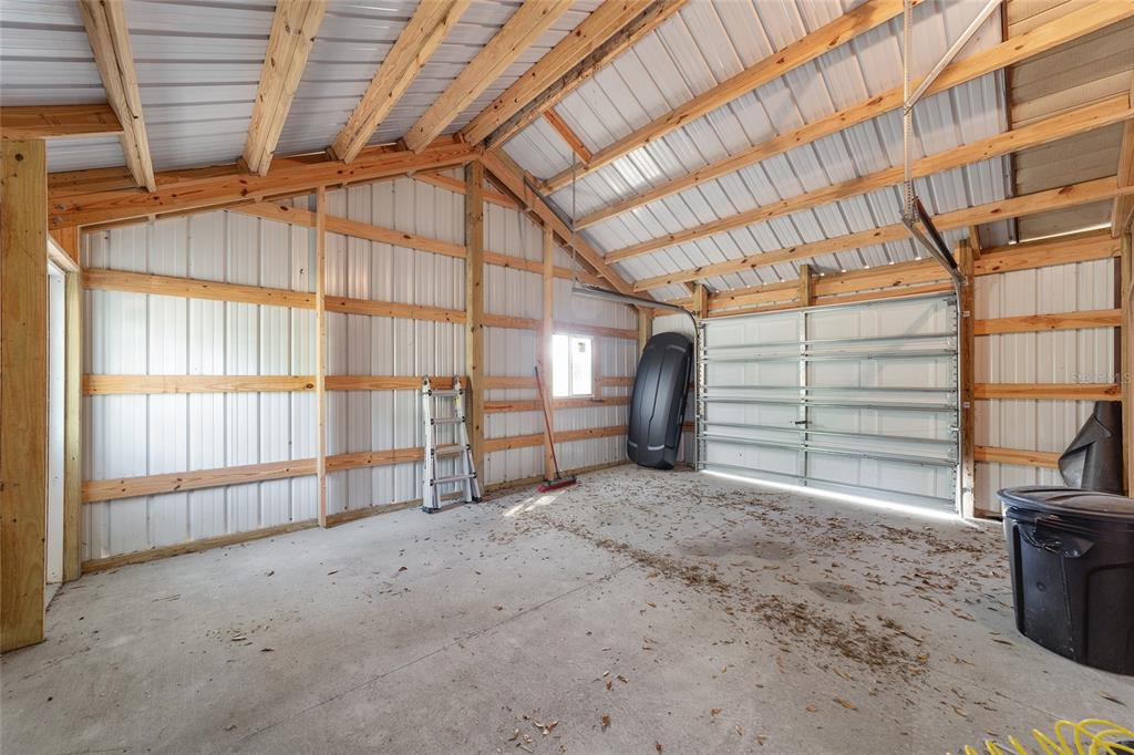 An interior view of a metal-sided garage with exposed wooden framing and a concrete floor — 14020 NW 160TH AVENUE, WILLISTON, FL