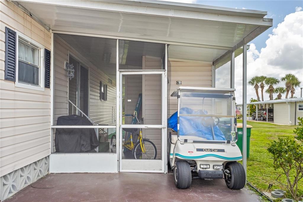 A covered patio with a screen enclosure, a golf cart, and a bicycle — 2100 KINGS HIGHWAY UNIT 175, PORT CHARLOTTE, FL