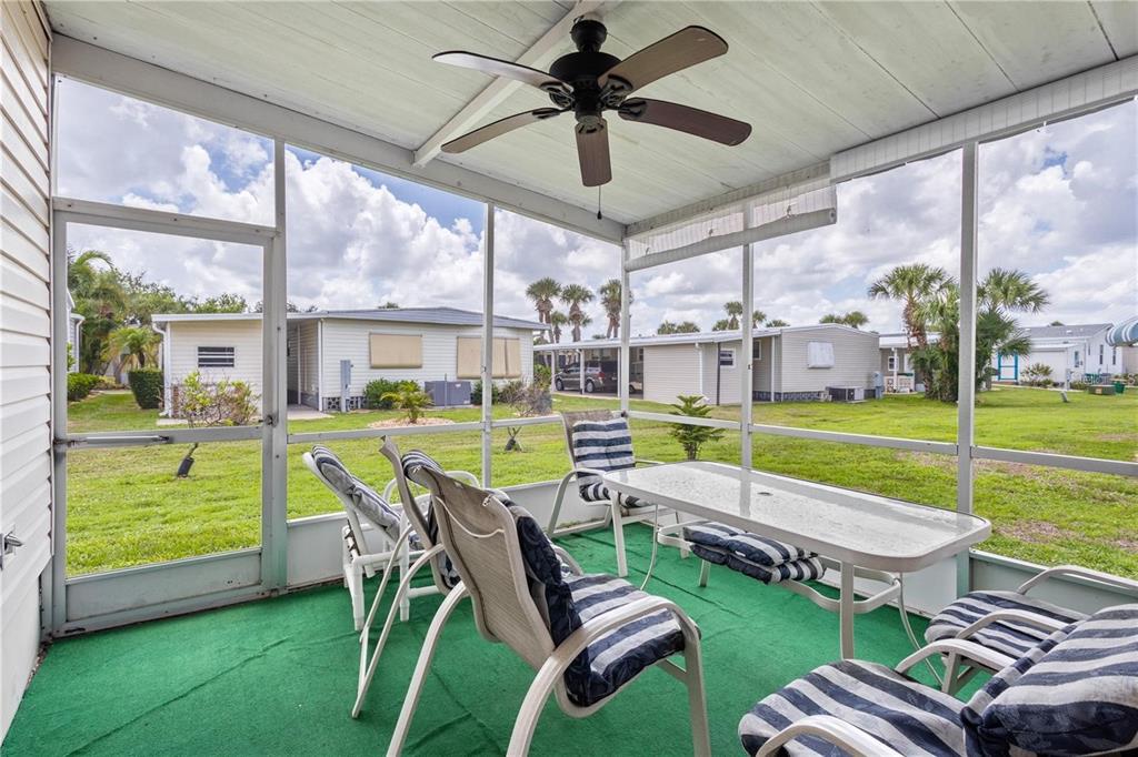 A screened-in porch with green outdoor carpeting, patio furniture, and a ceiling fan — 2100 KINGS HIGHWAY UNIT 175, PORT CHARLOTTE, FL