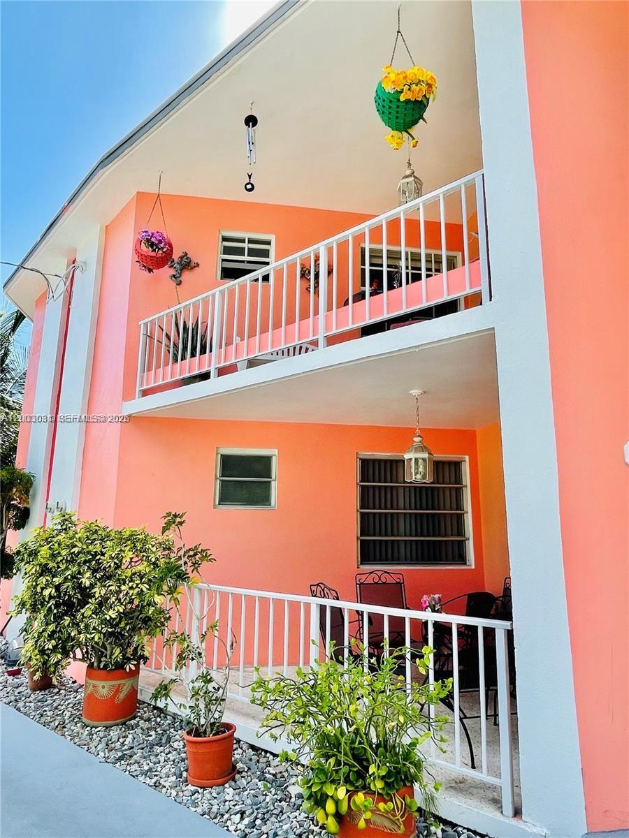 A two-story peach-colored building features white railings, potted plants, and a gravel ground area — 270 NW 34th Ter, Miami FL 33127, MIAMI, FL