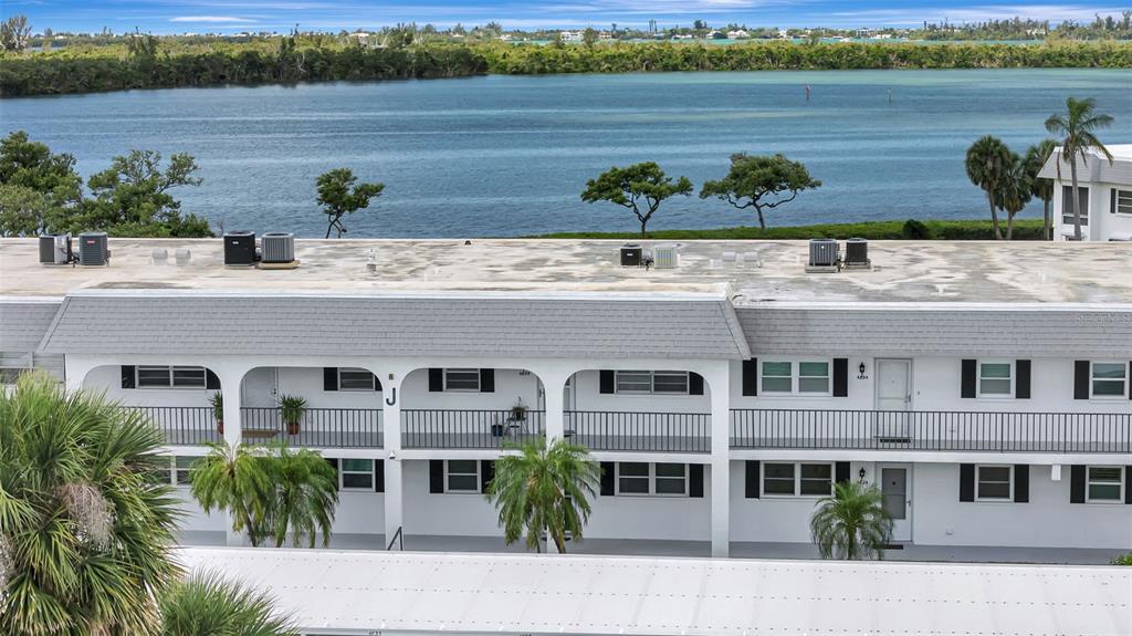 An exterior view of a two-story apartment building with balconies overlooking a body of water — 4835 INDEPENDENCE DRIVE, BRADENTON, FL
