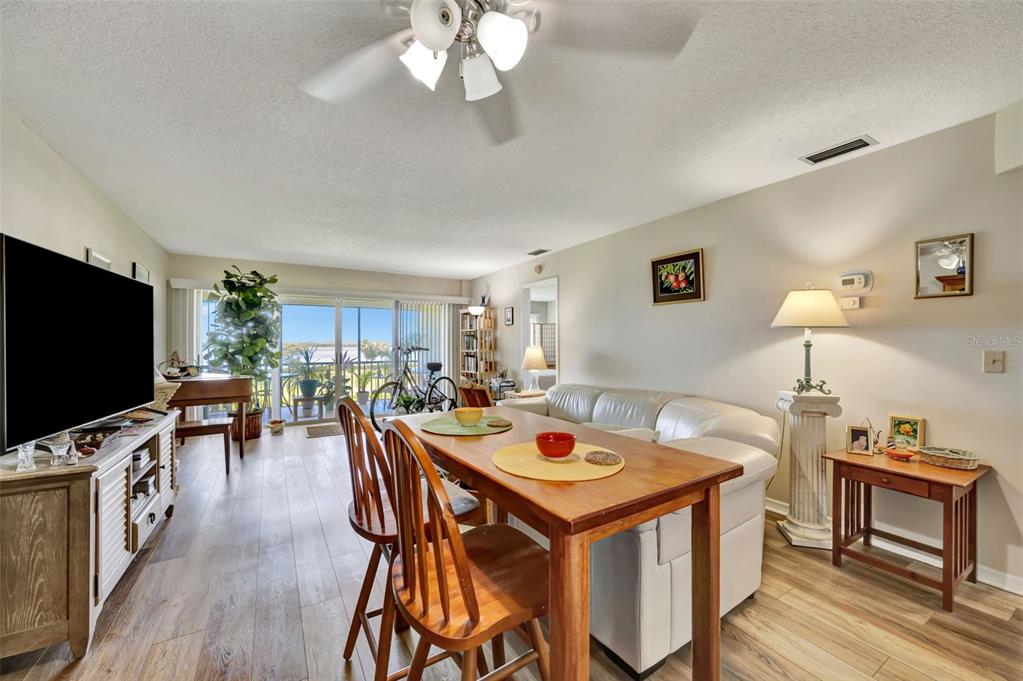 A living and dining room features wood-look flooring, a white sofa, and a sliding glass door — 4835 INDEPENDENCE DRIVE, BRADENTON, FL
