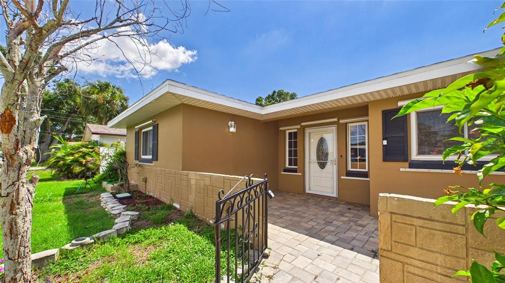 A tan house with a paved walkway, a wrought iron gate, and a white front door — 10310 110TH WAY, SEMINOLE, FL