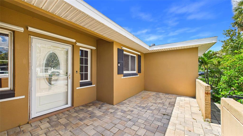 A paved patio sits in front of a house with a tan exterior and white door — 10310 110TH WAY, SEMINOLE, FL
