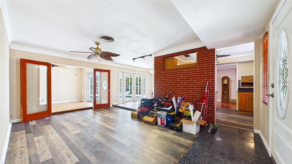An interior view shows a living area with wood-look flooring, a brick wall, and French doors — 10310 110TH WAY, SEMINOLE, FL