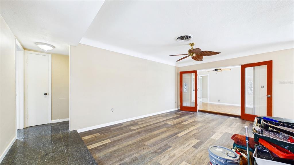 A room with wood-look flooring, a ceiling fan, and glass-paneled doors leading to another room — 10310 110TH WAY, SEMINOLE, FL