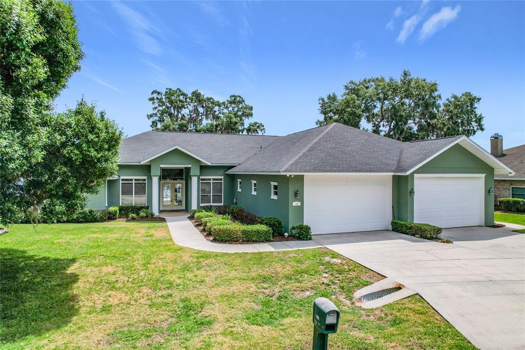 A green single-story house features a two-car garage and a front walkway leading to the entrance — 134 BAYBERRY DRIVE, POLK CITY, FL