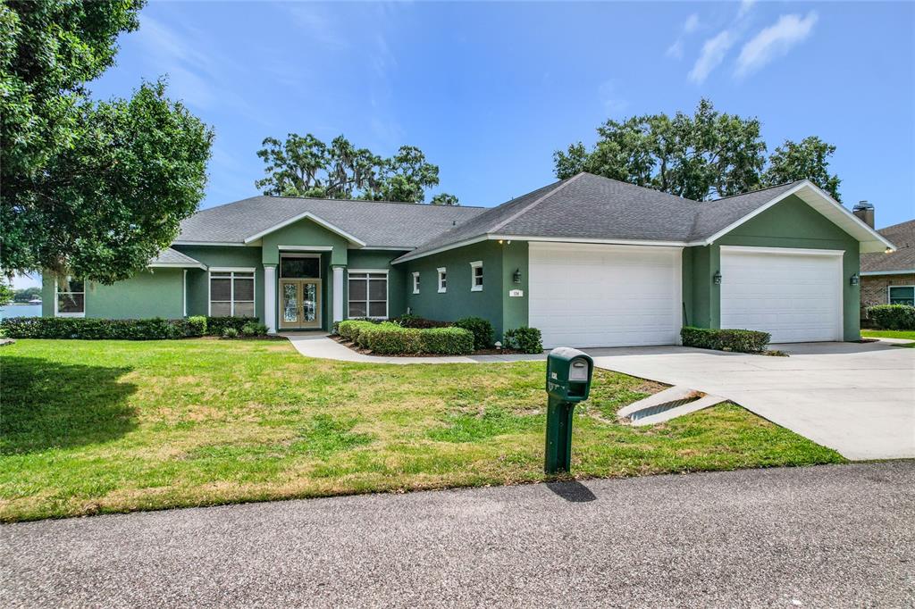 A green single-story house with a two-car garage and a paved driveway — 134 BAYBERRY DRIVE, POLK CITY, FL