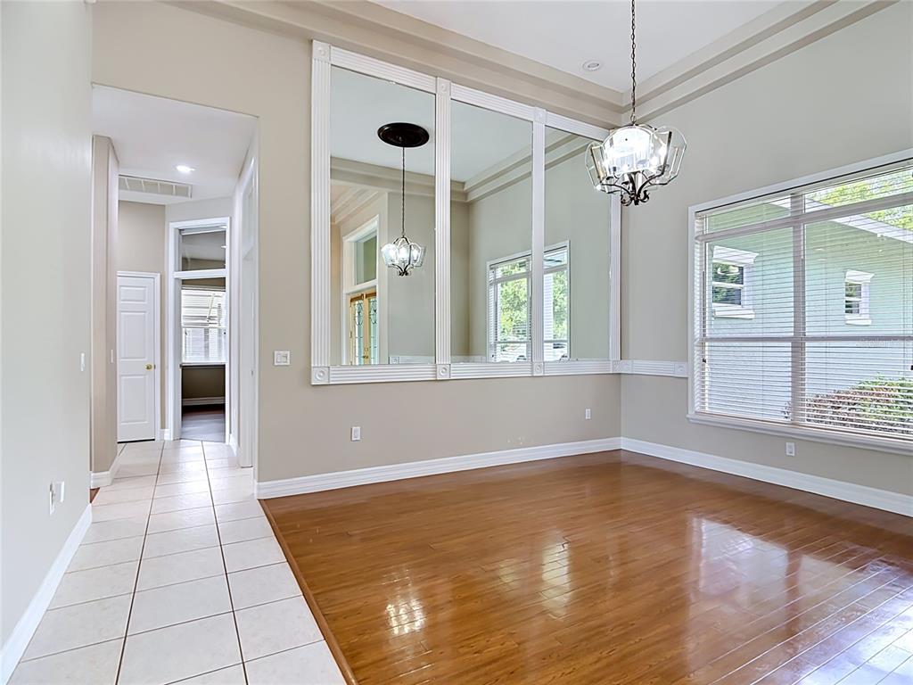 A dining room features hardwood floors, a large wall mirror, and a crystal chandelier — 134 BAYBERRY DRIVE, POLK CITY, FL