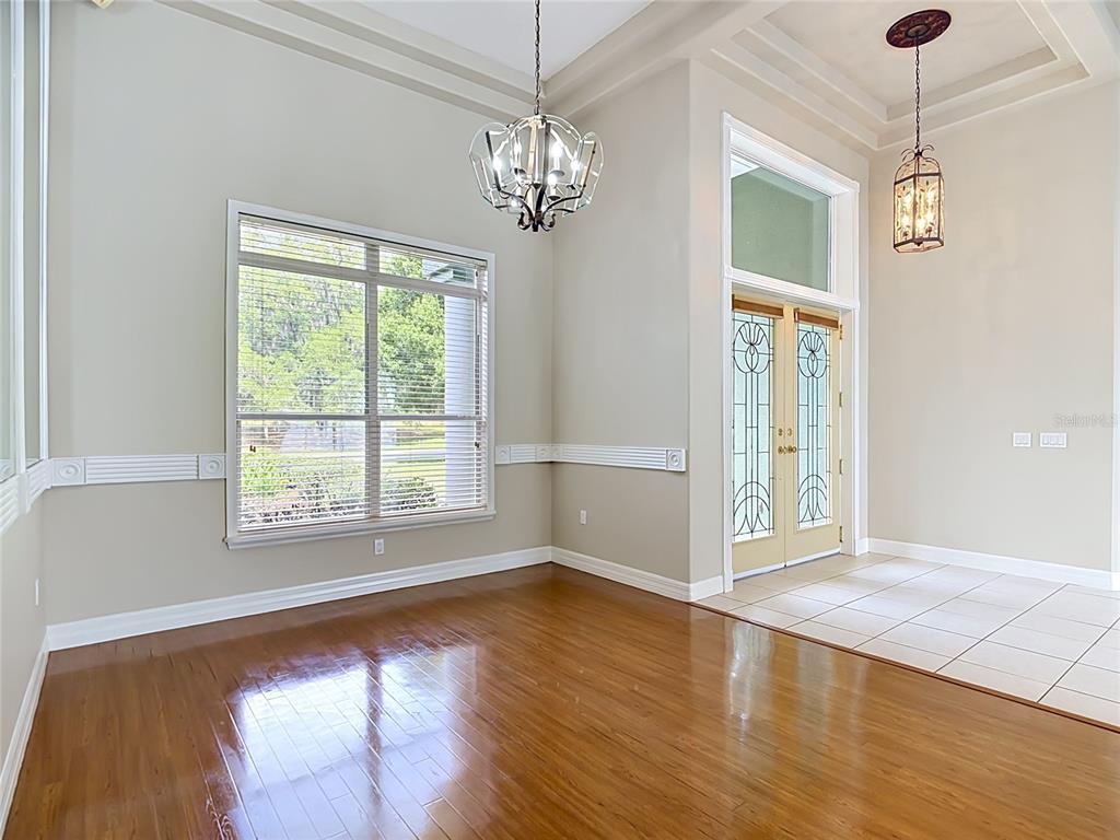 A room with hardwood floors, a large window, a chandelier, and double glass-paneled doors — 134 BAYBERRY DRIVE, POLK CITY, FL