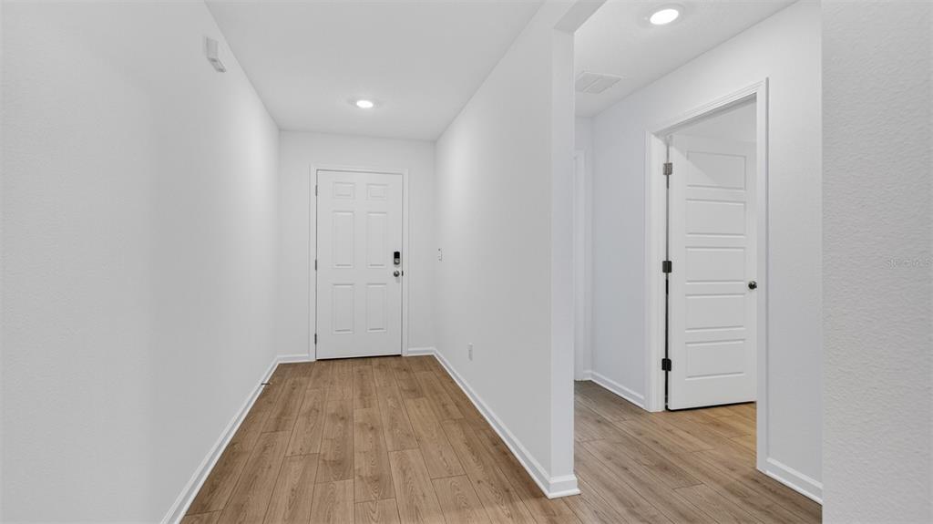 A bright entryway features white walls, light wood-look flooring, and a white paneled front door — 29 SAWDUST LANE, PALM COAST, FL