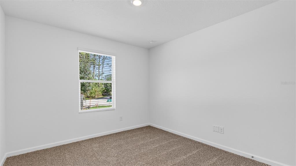 An empty bedroom features light gray walls, beige carpeting, and a single window with blinds — 29 SAWDUST LANE, PALM COAST, FL