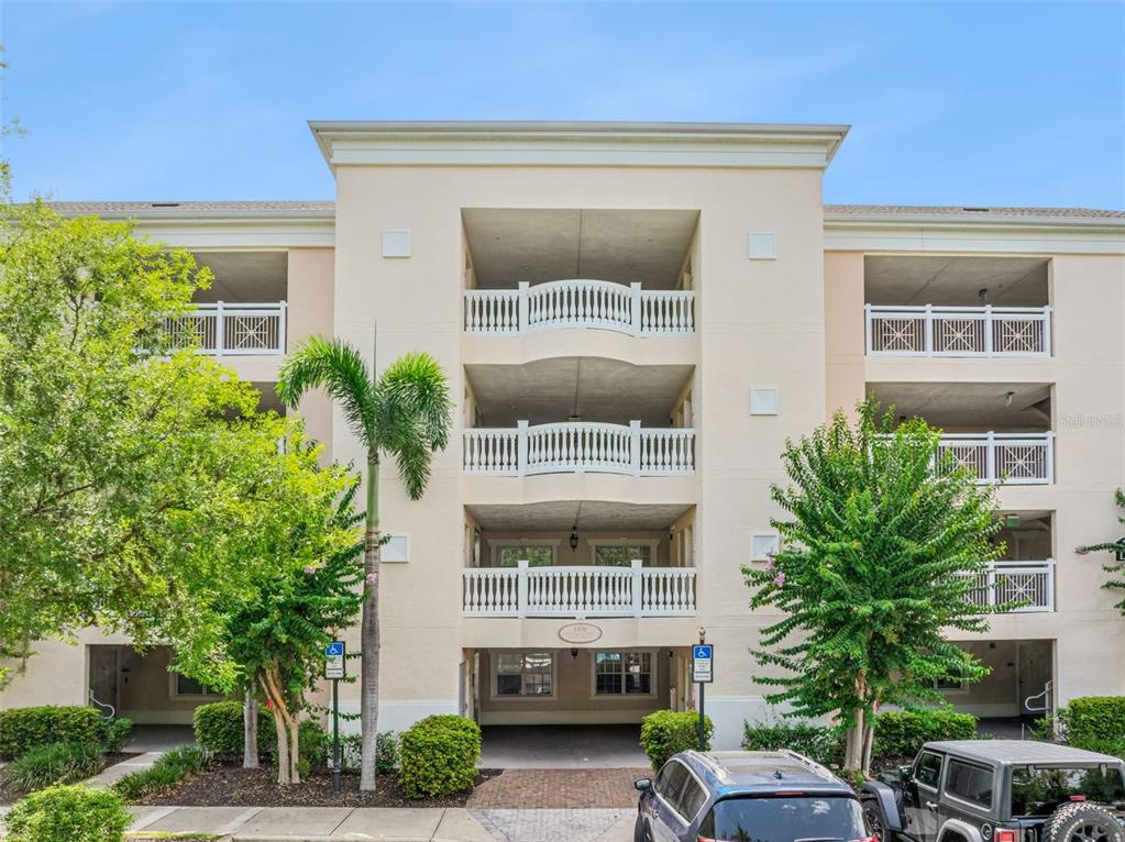 The exterior of a multi-story apartment building features balconies with white railings and palm trees — 1356 CENTRE COURT RIDGE DRIVE UNIT 303, KISSIMMEE, FL