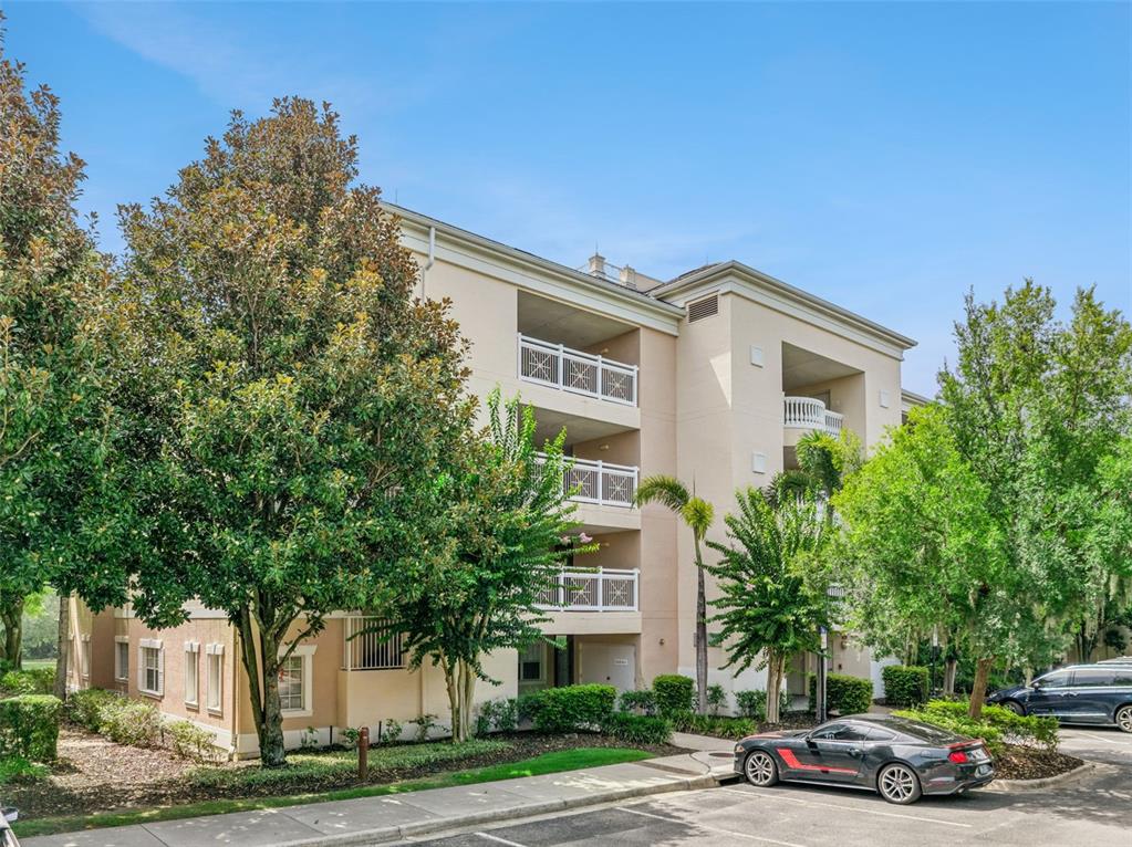 A three-story apartment building with balconies and a parking lot in the foreground — 1356 CENTRE COURT RIDGE DRIVE UNIT 303, KISSIMMEE, FL