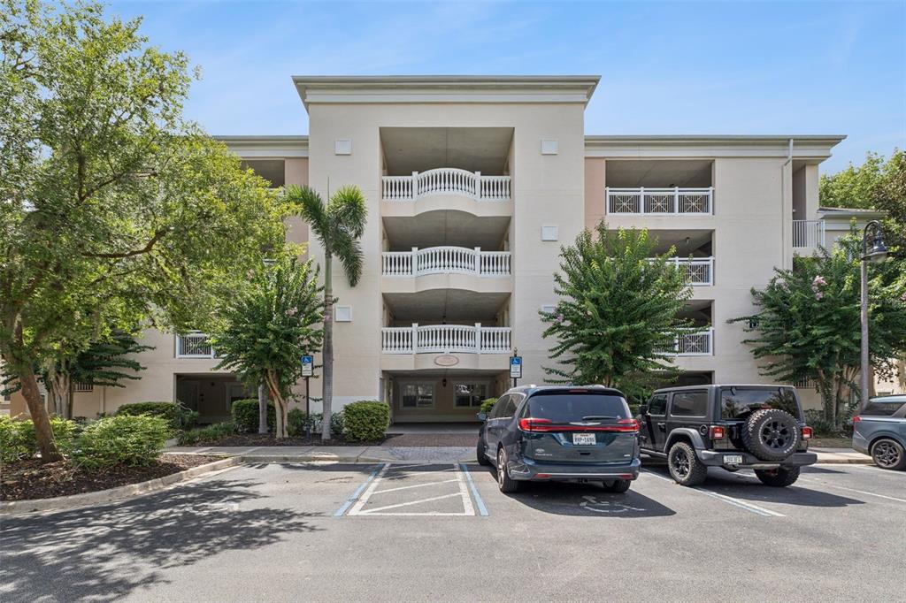 A multi-story apartment building with balconies and a parking lot in the foreground — 1356 CENTRE COURT RIDGE DRIVE UNIT 303, KISSIMMEE, FL