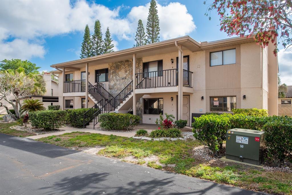 A two-story apartment building with a stone facade, exterior stairs, and a black metal railing — 9910 EAGLES POINT CIRCLE UNIT 3, PORT RICHEY, FL