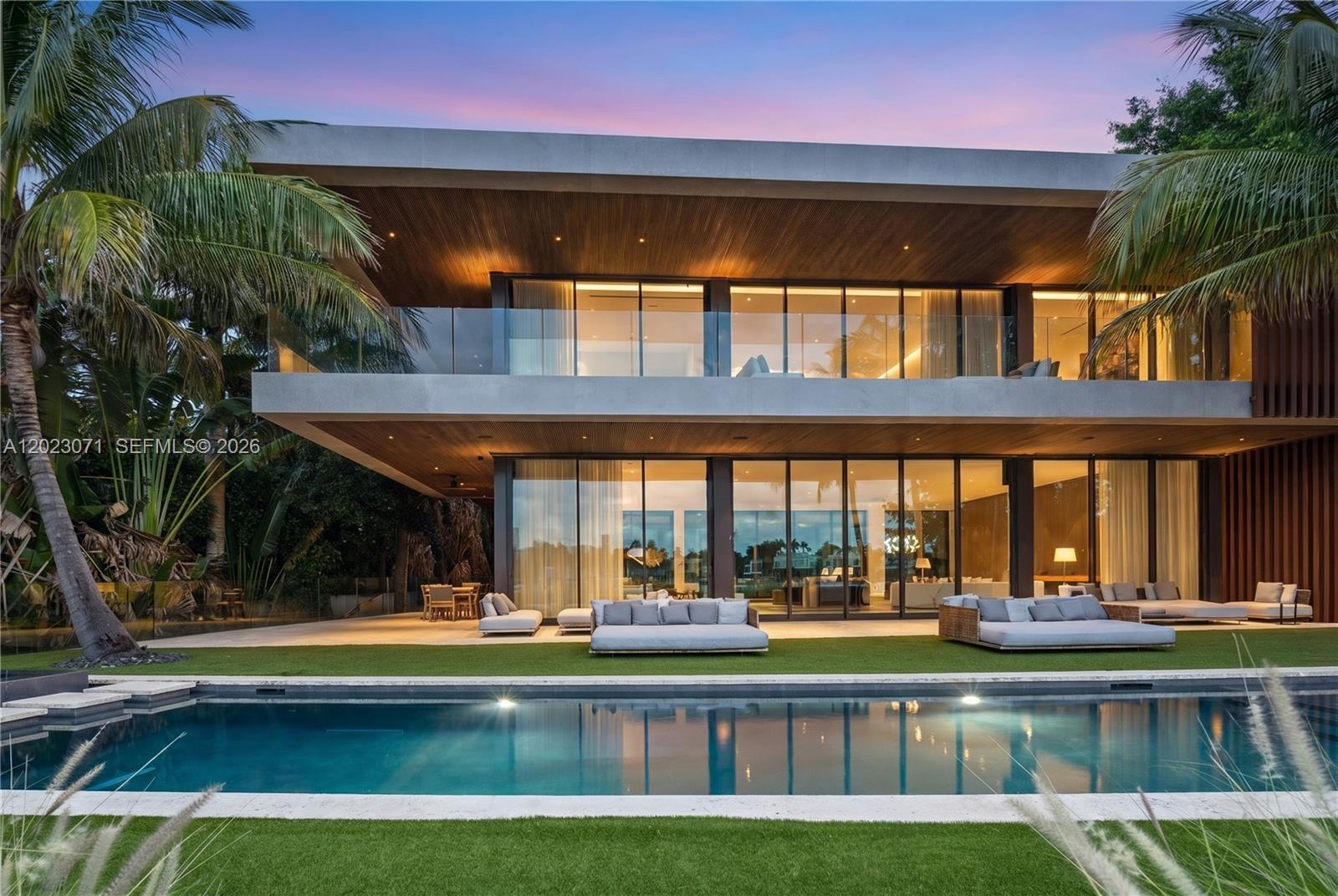 A modern two-story house with floor-to-ceiling glass walls overlooks a swimming pool and lawn — 28 W Dilido Dr, Miami Beach FL 33139, MIAMI BEACH, FL
