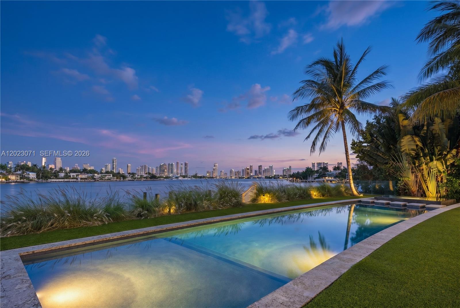 An infinity pool overlooks a waterfront lawn with a city skyline in the background — 28 W Dilido Dr, Miami Beach FL 33139, MIAMI BEACH, FL
