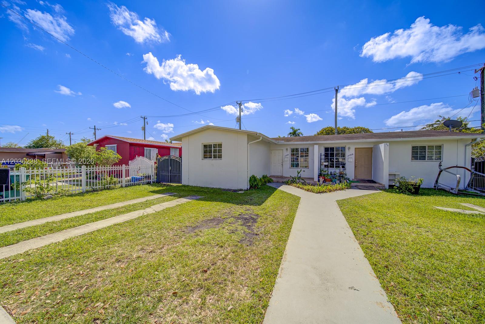 A single-story white house features a Y-shaped concrete walkway and a white picket fence — 11250 SW 7th St, Sweetwater FL 33174, SWEETWATER, FL