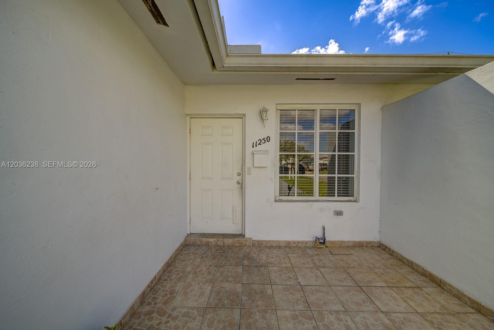 A white exterior door and a grid-pane window are set within a tiled entryway — 11250 SW 7th St, Sweetwater FL 33174, SWEETWATER, FL