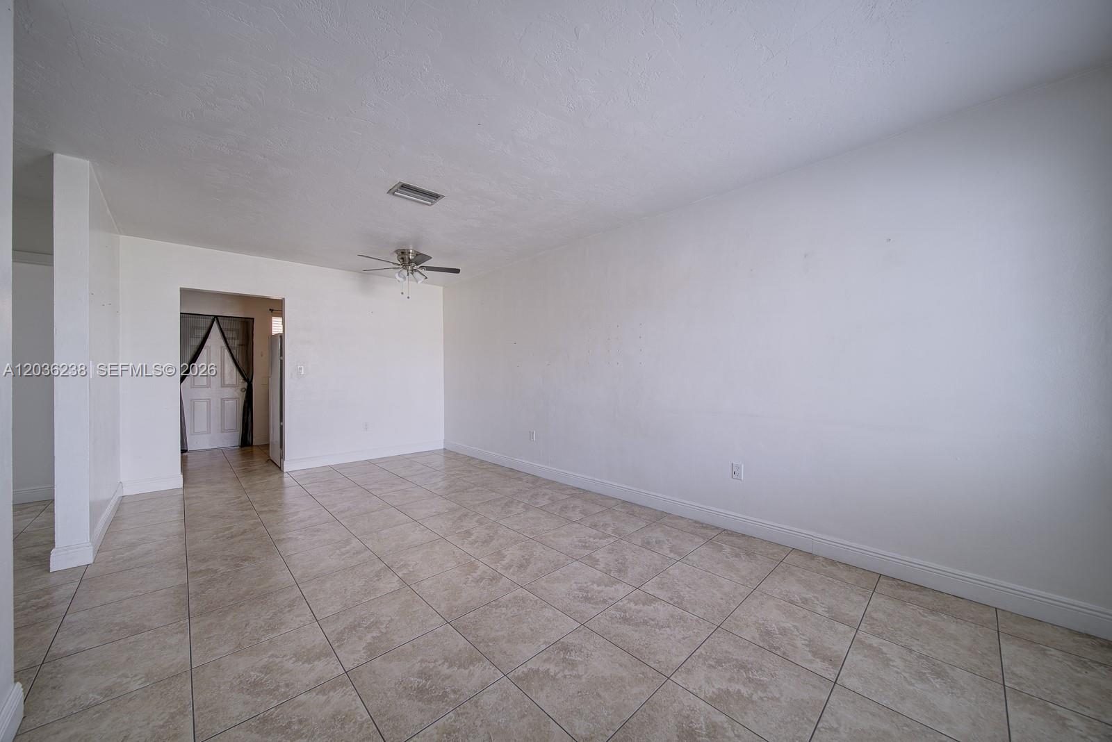 An empty room features white walls, a ceiling fan, and beige tiled flooring — 11250 SW 7th St, Sweetwater FL 33174, SWEETWATER, FL