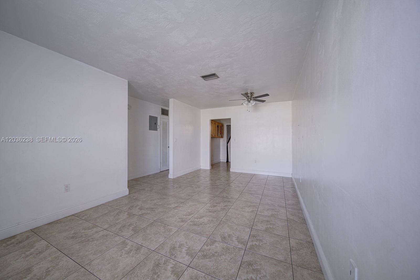 An empty room features white walls, a ceiling fan, and light-colored square floor tiles — 11250 SW 7th St, Sweetwater FL 33174, SWEETWATER, FL