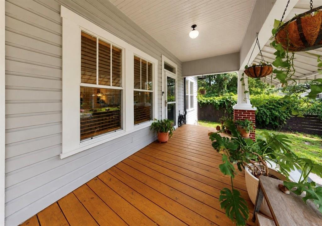 A screened-in porch features a wooden deck, outdoor furniture, a chandelier, and bamboo shades — 6702 N ELIZABETH STREET, TAMPA, FL