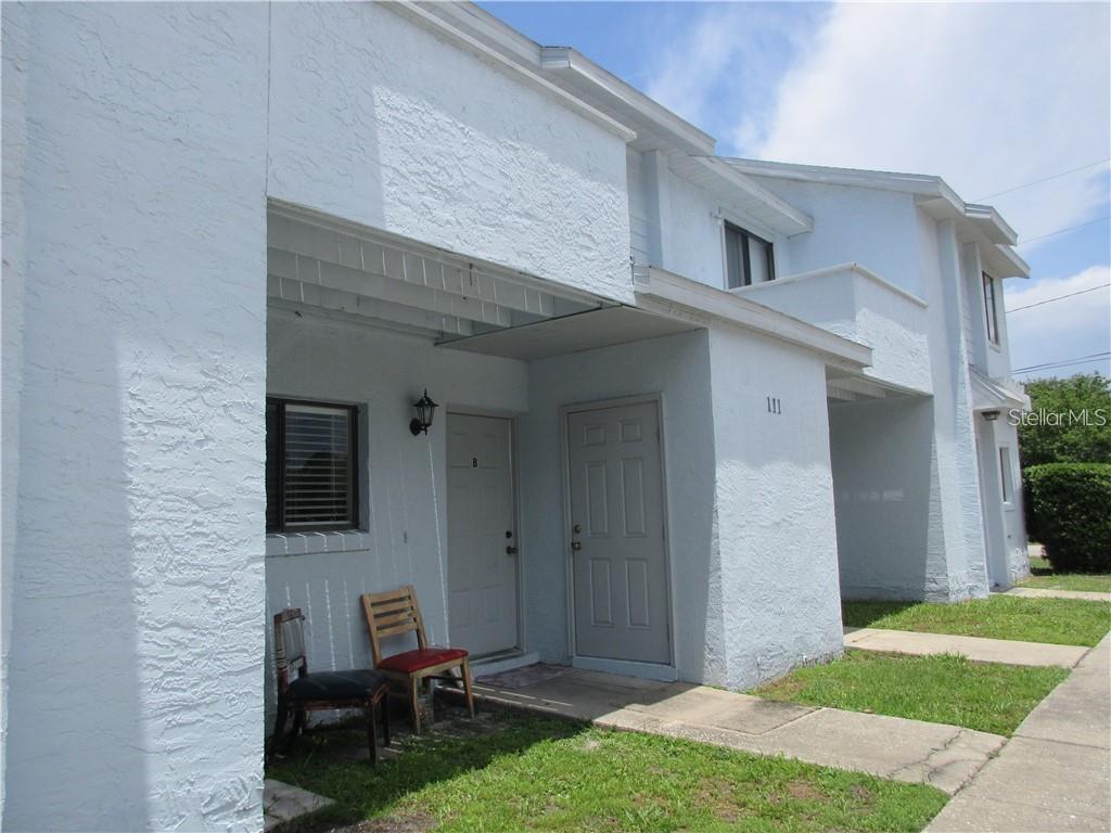 A white two-story townhouse exterior features two gray entry doors and a small concrete walkway — 111 MICHELLE LANE UNIT B, KISSIMMEE, FL