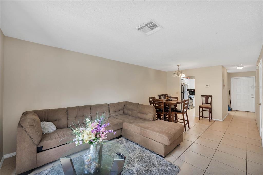 A living room with a brown sectional sofa, a glass coffee table, and adjacent dining area — 111 MICHELLE LANE UNIT B, KISSIMMEE, FL