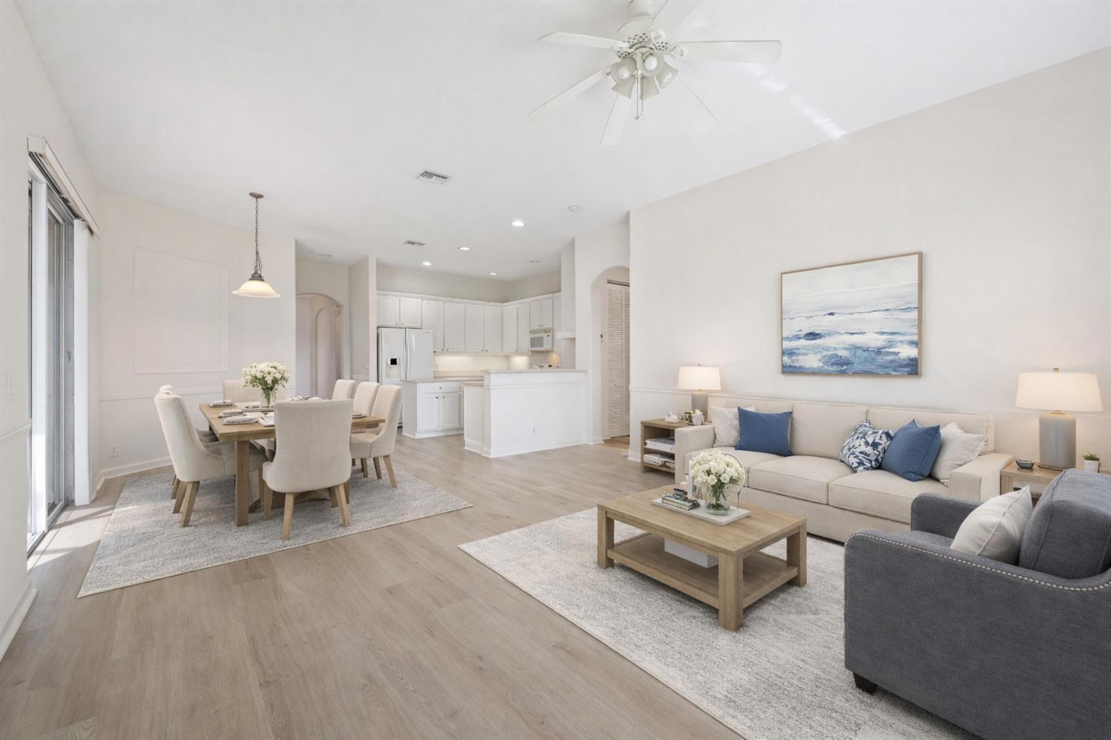 An open-concept living and dining area features light wood flooring, white cabinetry, and neutral furniture — 9531 Lantern Bay Circle, West Palm Beach FL 33411, WEST PALM BEACH, FL