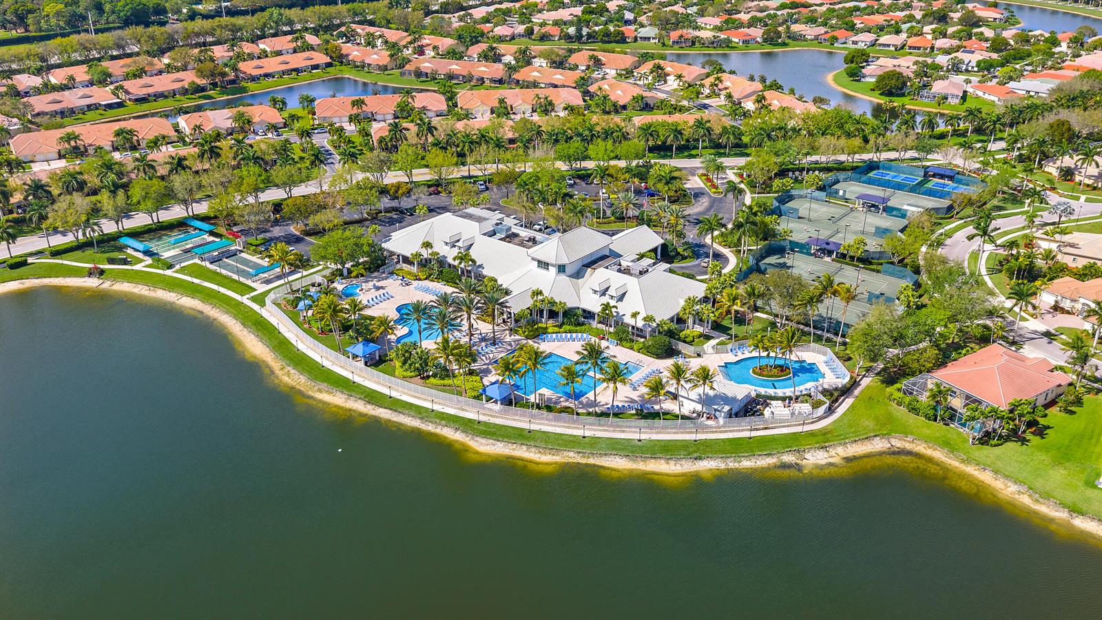 Aerial view of a community clubhouse featuring swimming pools, tennis courts, and surrounding residential homes — 9531 Lantern Bay Circle, West Palm Beach FL 33411, WEST PALM BEACH, FL