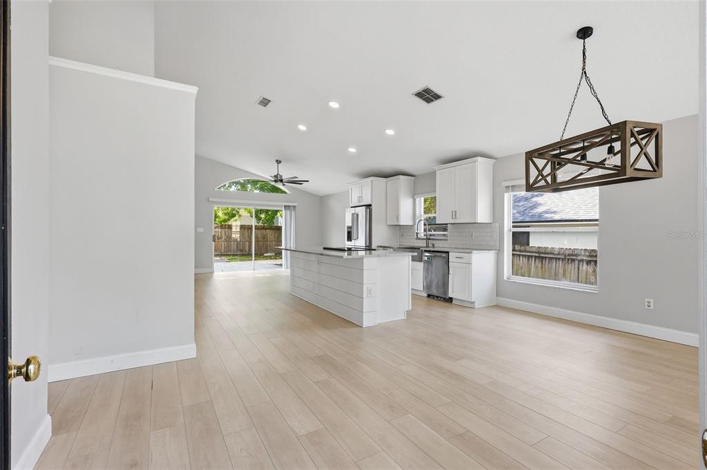 A bright, open-concept kitchen and dining area features white cabinetry, a central island, and light-colored flooring — 1960 AQUARIUS COURT, OVIEDO, FL