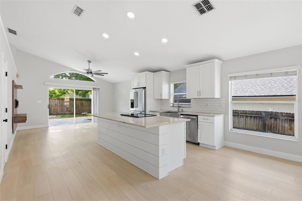 A bright kitchen with a white island, stainless steel appliances, and light wood flooring — 1960 AQUARIUS COURT, OVIEDO, FL