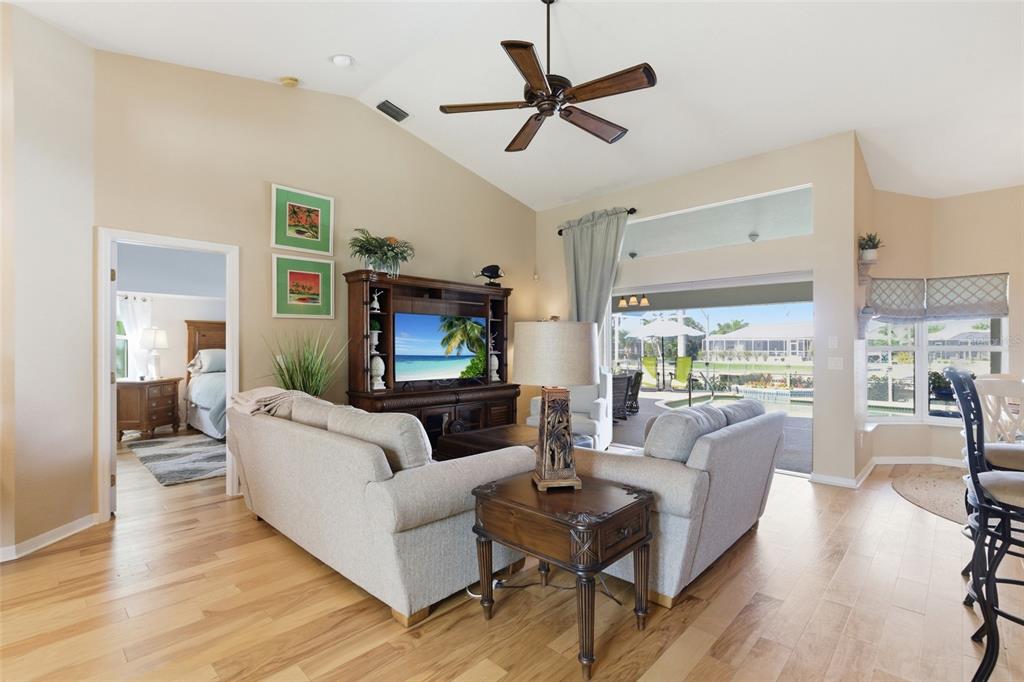 A living room features a vaulted ceiling, light wood floors, and a view of a pool — 1318 PENGUIN COURT, PUNTA GORDA, FL