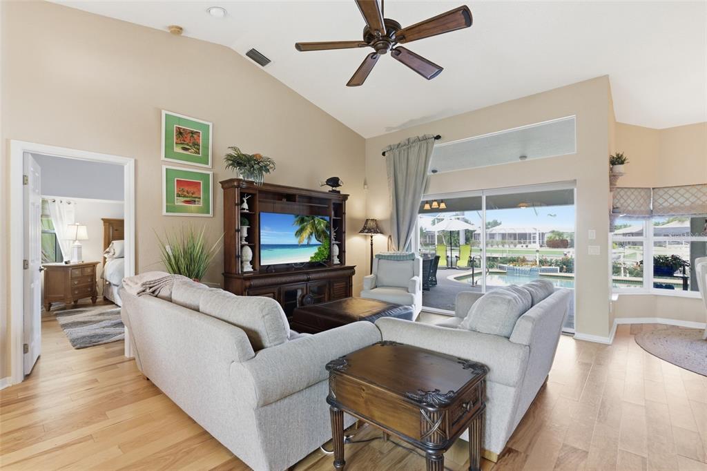 A living room with light wood floors, a vaulted ceiling, and a view of a pool — 1318 PENGUIN COURT, PUNTA GORDA, FL