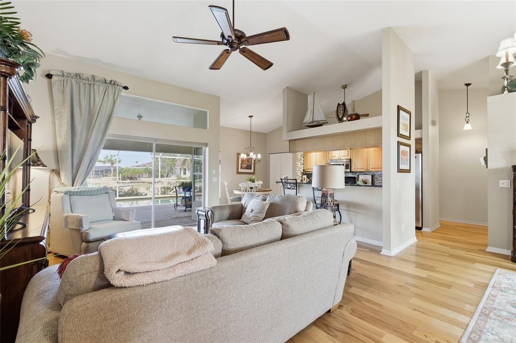 A living room with a beige sofa, hardwood floors, and a view of the pool — 1318 PENGUIN COURT, PUNTA GORDA, FL