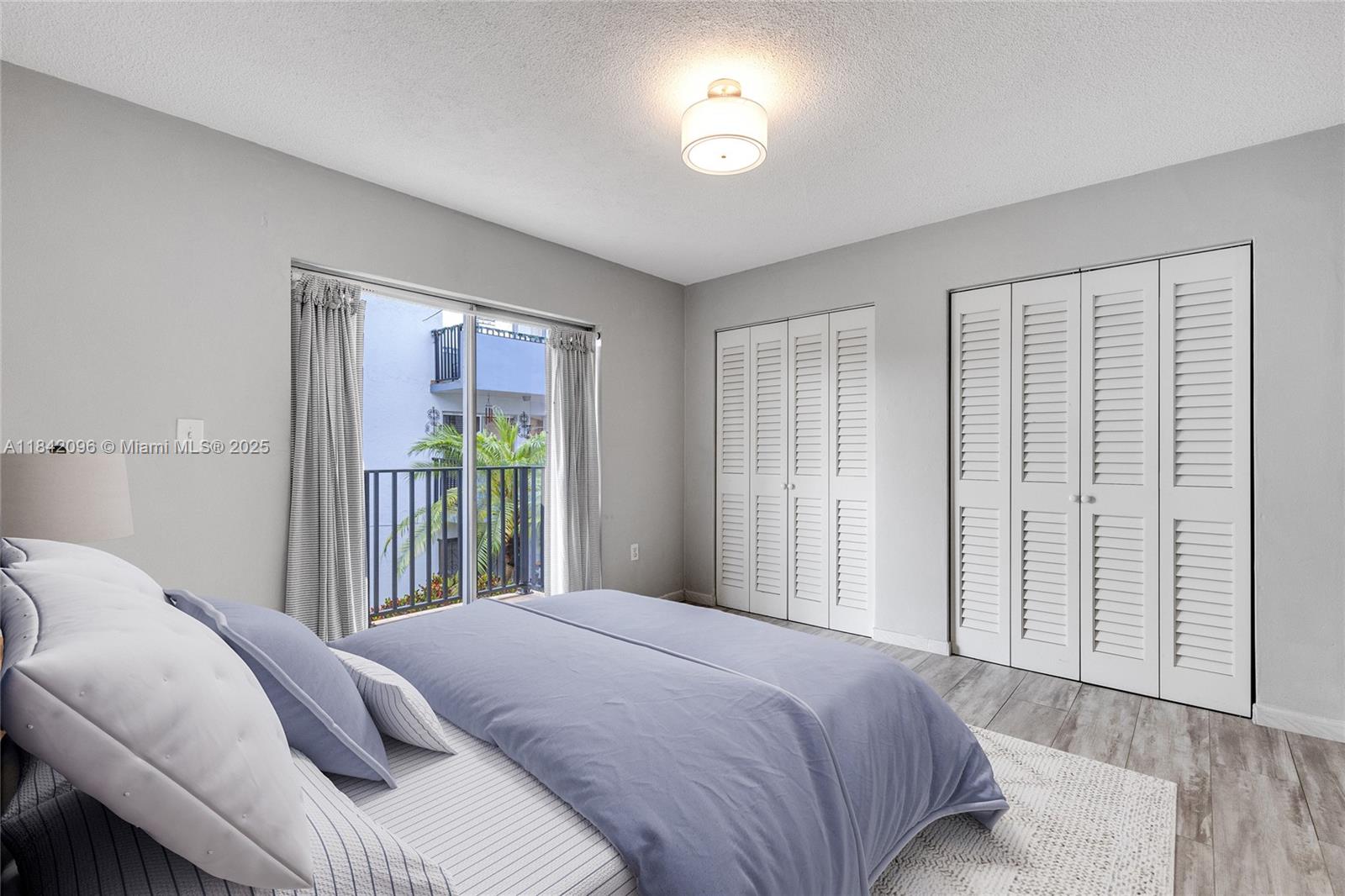 A bedroom features a bed, louvered closet doors, and a sliding glass door to a balcony — 2465 SW 18th Avenue # 3208, Miami FL 33145, MIAMI, FL