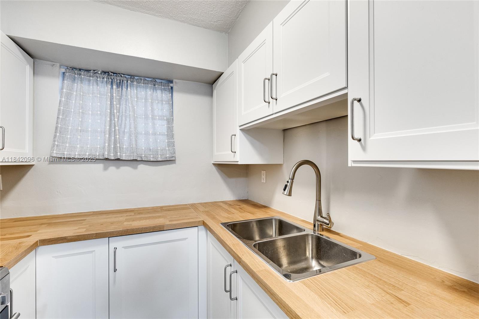 A kitchen features white cabinets, a light wood countertop, and a stainless steel double sink — 2465 SW 18th Avenue # 3208, Miami FL 33145, MIAMI, FL