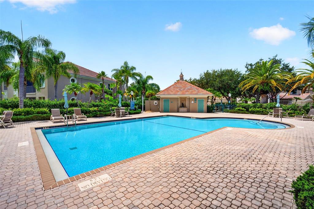 A swimming pool with a surrounding brick patio and a small pool house building — 7492 BOTANICA PARKWAY UNIT 102, SARASOTA, FL
