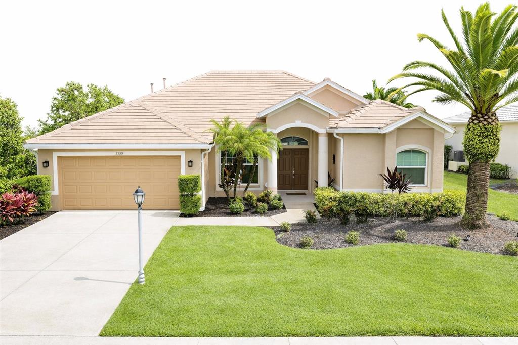 A single-story tan house with a tile roof, a two-car garage, and a palm tree — 2520 SILVER PALM ROAD, NORTH PORT, FL