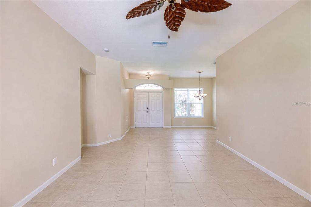An empty room with beige walls, tile flooring, a ceiling fan, and a front entryway — 2520 SILVER PALM ROAD, NORTH PORT, FL