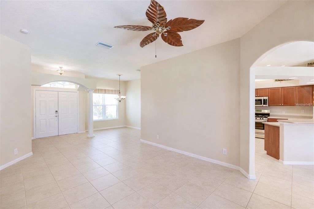 An open-concept living and dining area features tile flooring, a palm-leaf ceiling fan, and columns — 2520 SILVER PALM ROAD, NORTH PORT, FL