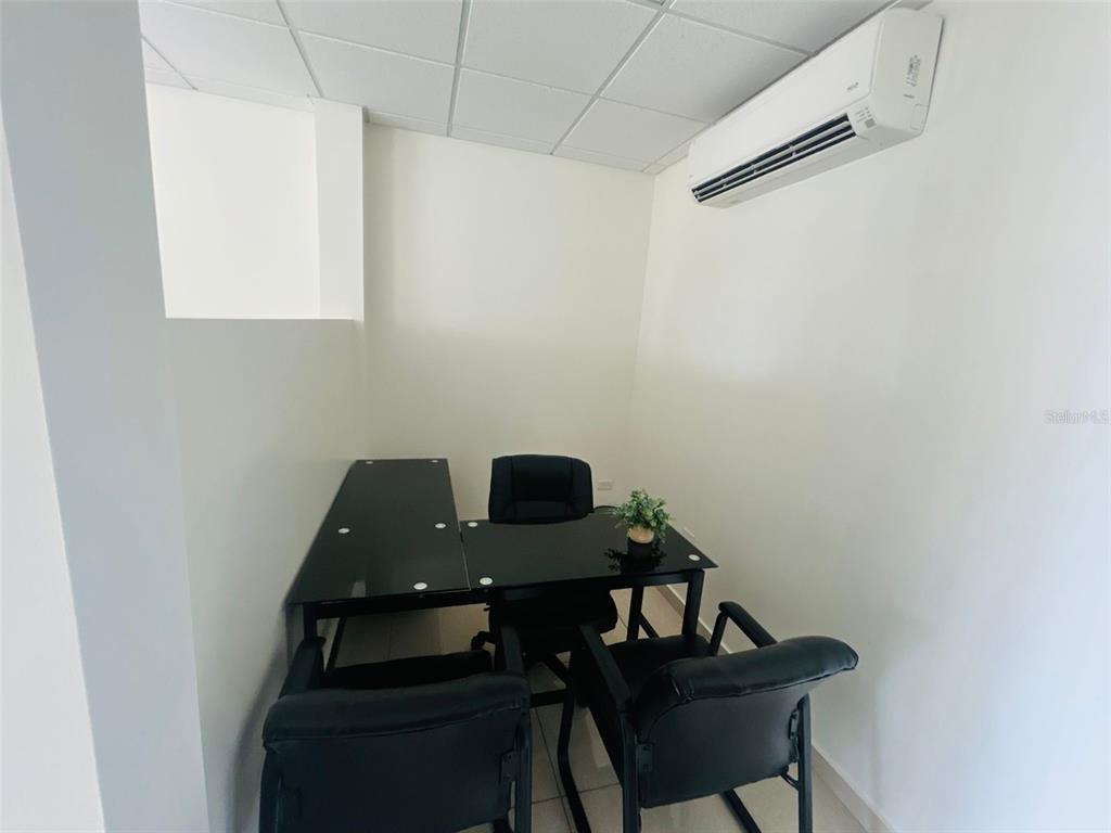 A small office space features a black desk, three chairs, and a wall-mounted air conditioner — 1396 CALLE BONITA, PONCE, PR