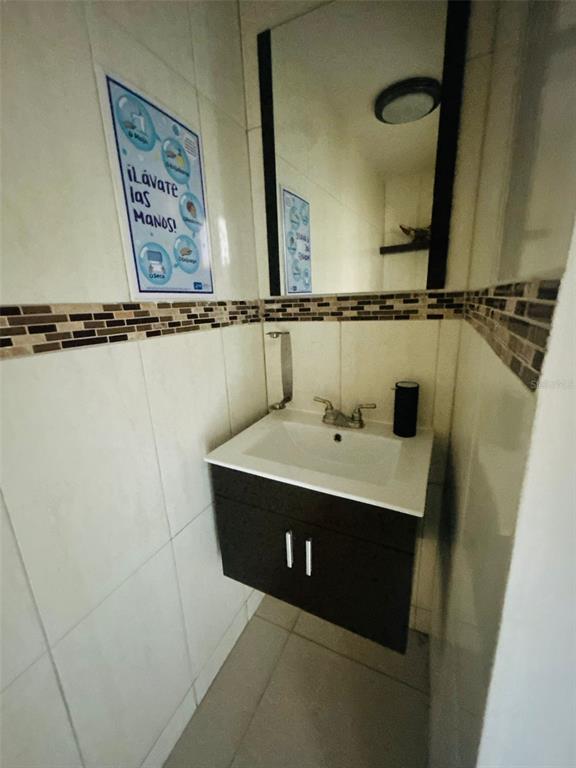 A small bathroom features a white sink, dark vanity cabinet, mirror, and tiled walls — 1396 CALLE BONITA, PONCE, PR