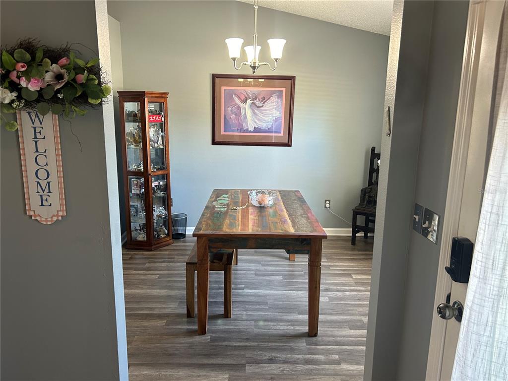 A dining room features a rustic wooden table, a glass display cabinet, and gray flooring — 4 LYSANDER LANE, PALM COAST, FL