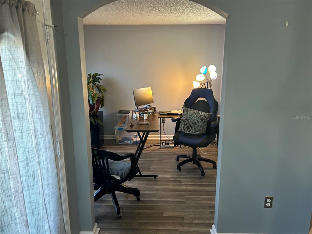 A home office with wood-look flooring, a desk, two chairs, and a decorative lamp — 4 LYSANDER LANE, PALM COAST, FL