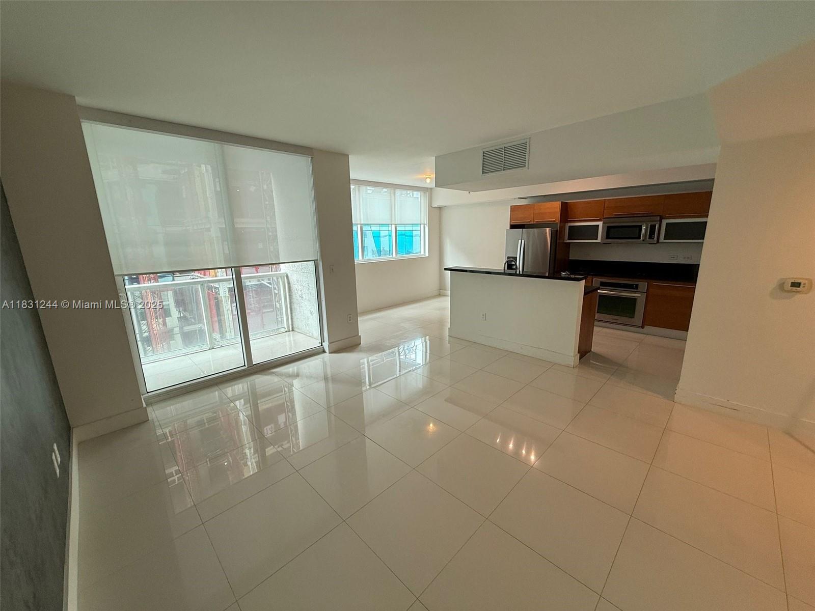 An open-concept living area features white tile flooring, a kitchen island, and floor-to-ceiling windows — 244 Biscayne Blvd # 908, Miami FL 33132, MIAMI, FL